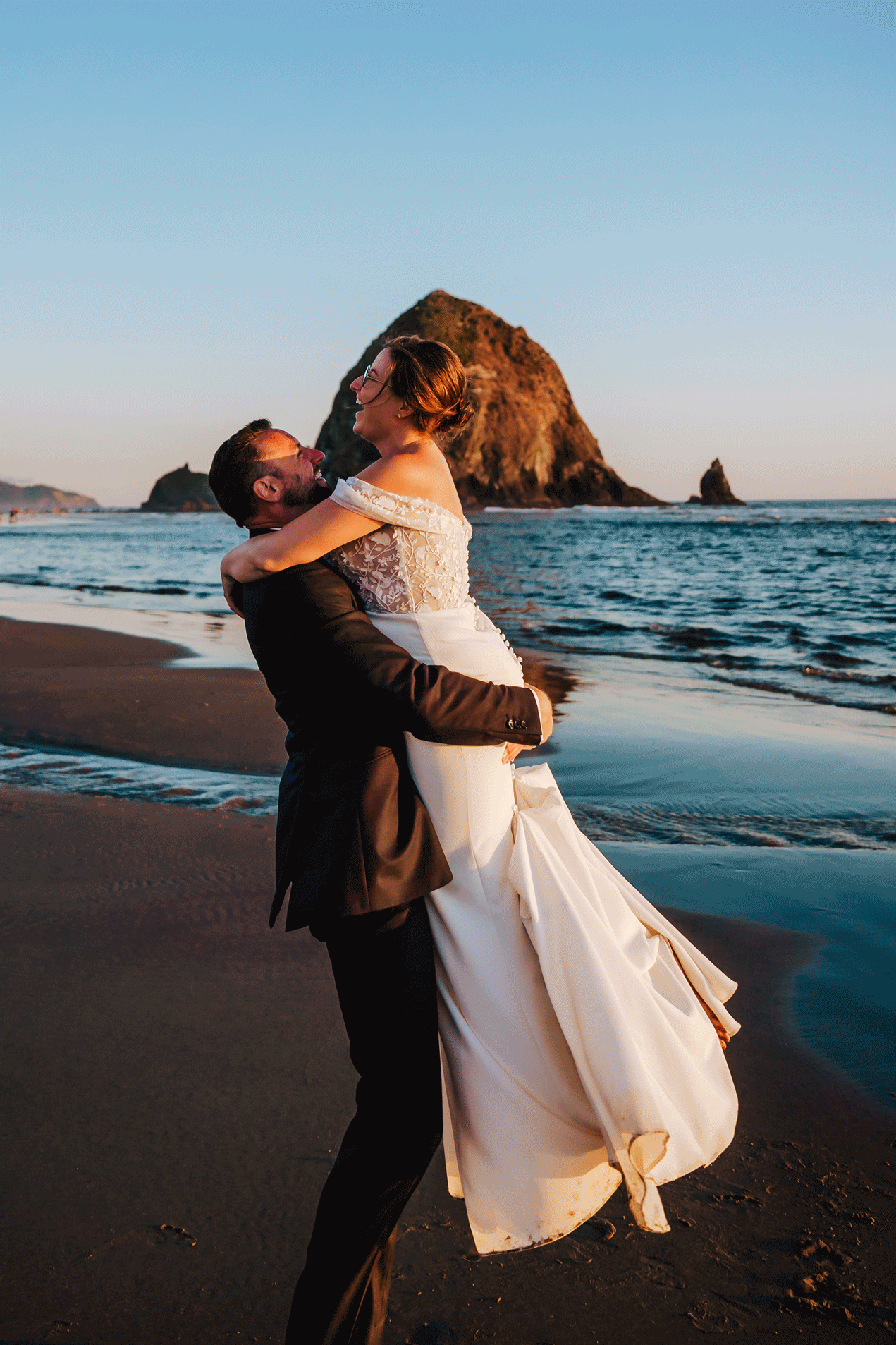 Newlyweds twirling in front of Haystack Rock during their Surfsand Resort Cannon Beach Micro Wedding on the Oregon Coast
